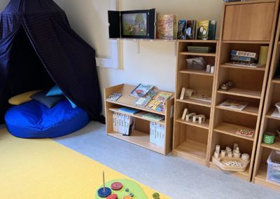 Lesezimmer in der Villa Kunterbunt mit einem Bücherregal, verschiedenen Spielen und einem Zelt